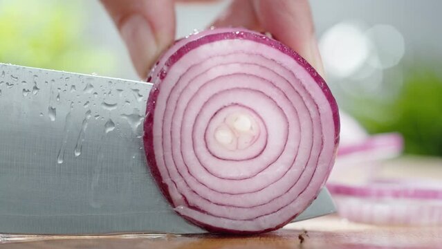 Cutting Red Onion Slice with Sharp Knife on the Wooden Chopping Board and Splashing Water in Slow