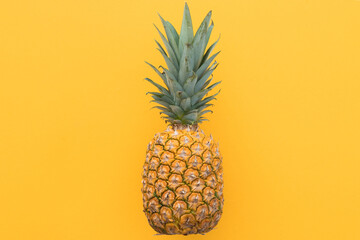 Ripe pineapple on a yellow background