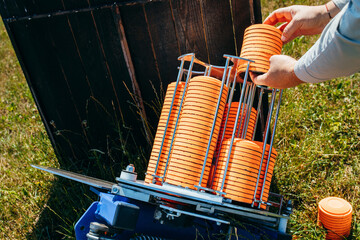 Close up hands of worker loading plat machine with orange shooting plate for shooting-ground...