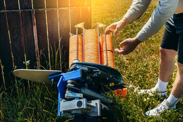 Close up hands of worker loading plat machine with orange shooting plate for shooting-ground...