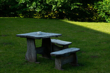 wooden table with benches and an ashtray in a resting place on green grass.