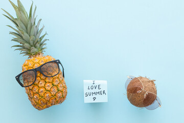 Hipster pineapple and coconut with sunglasses against a blue background