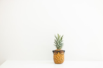 Ripe pineapple in sunglasses on a white background. Summer vacation. Hello summer