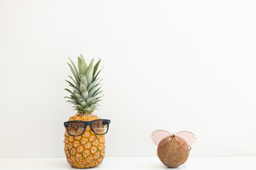 Ripe pineapple and coconut in sunglasses on a white background. Summer vacation. Hello summer