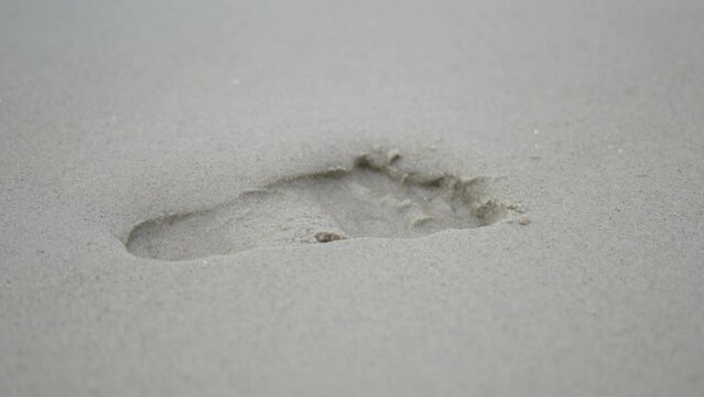 Footprints on the sandy beach were washed away by the sea waves.
