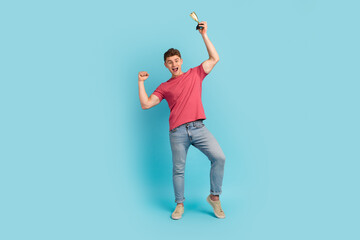 Fototapeta na wymiar Full length photo of young cheerful man rejoice victory hold trophy winner isolated over blue color background