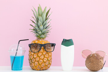 Fresh pineapple, coconut with sunglasses and cocktails, bottle of cream on color background