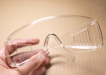 Protective glasses in hand, eye safety. Safety goggles, personal protective equipment. Eye shield mask. Plastic goggles, transparent glasses safety at construction works.