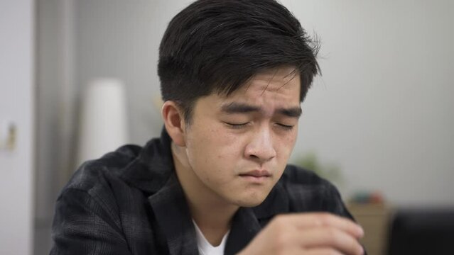 asian man working from home suffering poor eyesight is rubbing and patting his eyes while staring at computer screen trying to see clearly