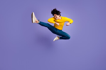 Fototapeta na wymiar Full body photo of energetic active person jumping leg kick copyspace isolated on violet color background
