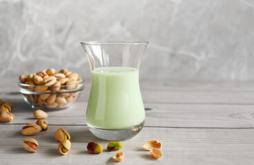 Pistachio milk in the glass on the wooden background. This milk is a great source of antioxidants, phytosterols, and heart healthy fats