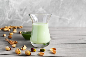 Pistachio milk in the glass and pistachio paste  on the wooden background
