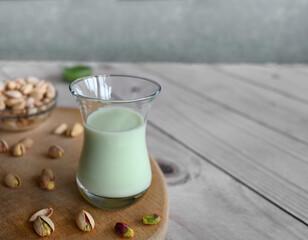 Pistachio milk in the glass on the wooden background. This milk is a great source of antioxidants, phytosterols, and heart healthy fats