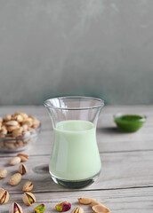 Pistachio milk in the glass and pistachio paste  on the wooden background
