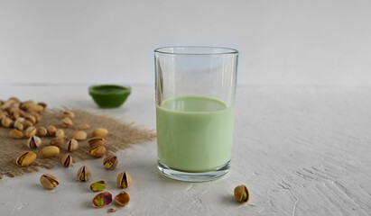 Pistachio milk in a glass, pistachio on a burlap and pistachio paste. This milk is a great source of antioxidants, phytosterols, and heart healthy fats