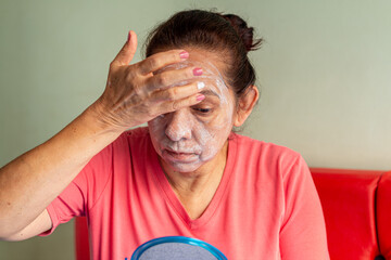 Mature woman using a facial mask for the skin. Self Care Incorporate concept. Older woman applying a beauty treatment on her face.