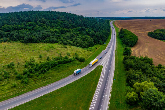trucks driving on asphalt road along the green fields. Aerial view landscape. drone photography. cargo delivery