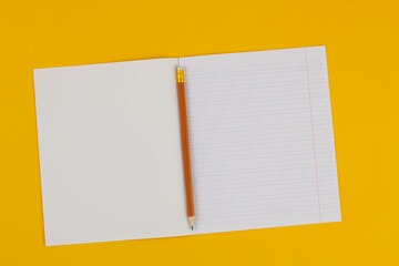 School notebook on a yellow background with copy space for text and pencil. Back to school. Blank sheet of paper with oblique lines in exercise book. school Supplies. Top view