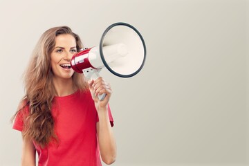 Smiling happy girl talking in megaphone, announcing discount promo, showing advertisement on top
