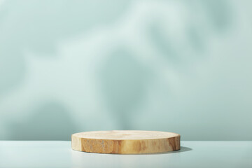 Wood slice podium with leaves shadows on blue background for cosmetic product mockup