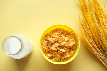  milk jar and corn flakes on yellow background 
