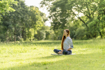 Naklejka na ściany i meble Young asia woman practicing meditation in the park. Throght happiness from inner peace.
