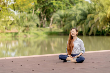 Fototapeta na wymiar Young Asian woman meditating near the canal at sunrise