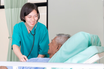 Fototapeta premium An Asian surgeon in Thailand meets an elderly patient who has undergone surgery to inquire about the condition and check the health of a patient lying on a hospital bed.