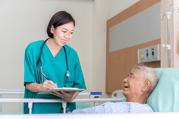 Fototapeta premium An Asian surgeon in Thailand meets an elderly patient who has undergone surgery to inquire about the condition and check the health of a patient lying on a hospital bed.