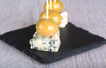 Canapes of blue cheese and large green olives on a black slate cutting board
