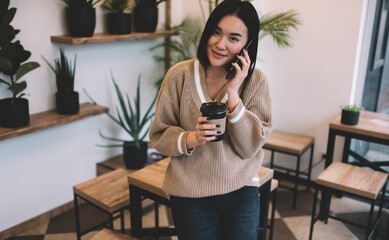 Asian girl with coffee talk on smartphone in cafe