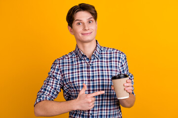 Happy man in casual shirt pointing finger at disposable cup paper cup coffee barista yellow background