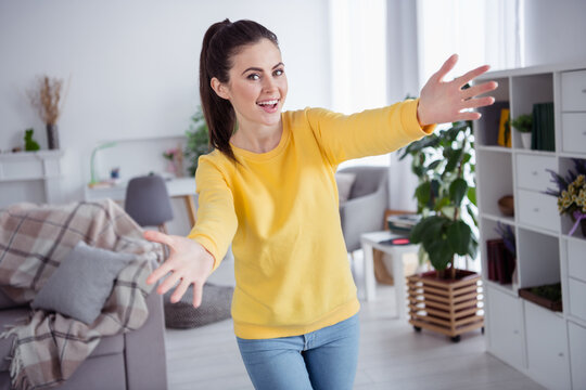 Photo of hospitable friendly nice cute pretty lady stretch hands invite hug wear yellow pullover comfortable home indoors