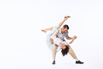 Portrait of young cheerful couple, man and woman, dancing swing isolated over white studio...