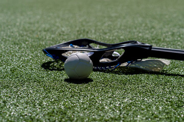 Lacrosse stick and white ball on green grass. Horizontal sport theme poster, greeting cards, headers, website and app