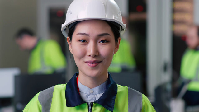 Close up portrait of chinese female industrial worker in hardhat and look at camera