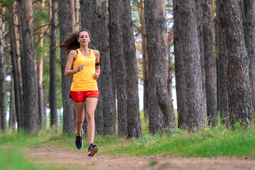 Running woman. Female runner jogging at the park. Girl training outdoors. Exercising on forest path. Healthy, fitness, wellness lifestyle. Sport, cardio, workout concept