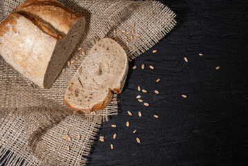 Sliced yeast grain bread with oats on dark concrete background