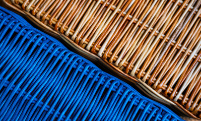 Natural braided background of basket of brown and painted blue tubes twisted from paper. Wicker surface of rustic craft basket made of eco vines, paper, close up of strips pattern. Handmade, handwork.