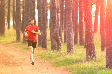 Running man. Male runner jogging at the park. Guy training outdoors. Exercising on forest path....