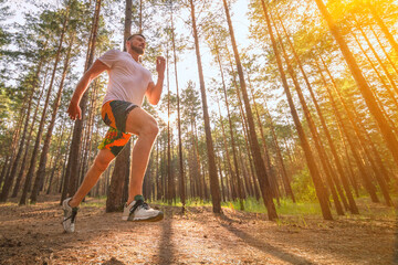Running man. Male runner jogging at the park. Guy training outdoors. Exercising on forest path....
