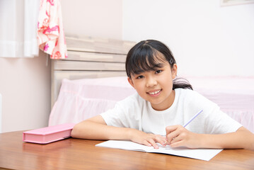 Naklejka premium 子供部屋で勉強をする小学生の女の子