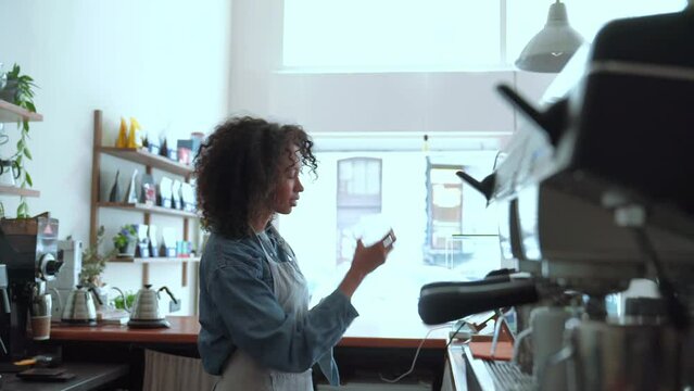 Handsome woman barista wiping glass cups while standing in cafe
