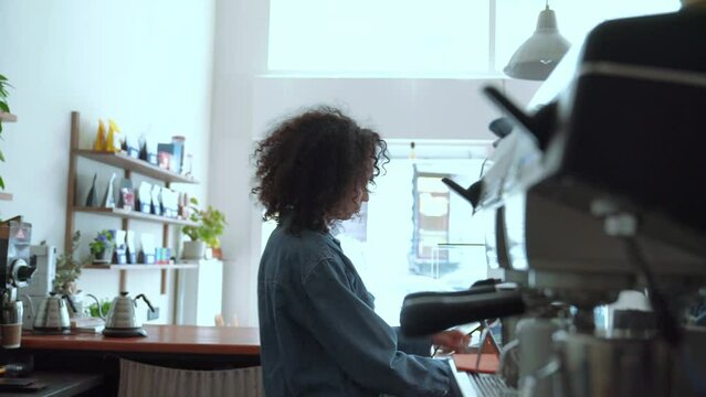 Concentrated woman barista puts on an apron and starting work in cafe