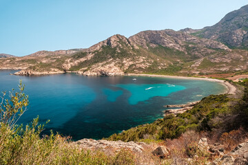Several jet skis and a catamaran in a large rocky cove on the west coast of Corsica and turquoise Mediterranean sea