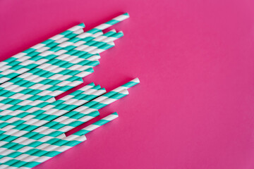 Fototapeta na wymiar top view of striped white and blue straws on pink background with copy space.