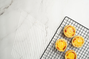 Traditional portuguese vanilla pudding puff pastry pastel de nata on black oven rack on marble...