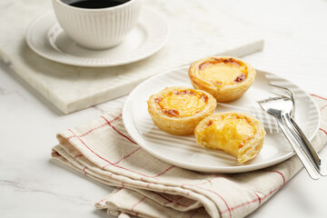 Traditional portuguese vanilla pudding puff pastry pastel de nata on black oven rack on white plate...