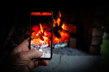 mans hand taking a picture of a roaring hot fire with a phone