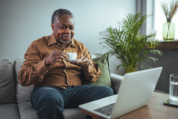 A senior black man enjoys a cup of coffee at home. Smiling senior man with cup of coffee day...